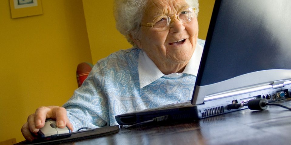 Senior elderly lady at home using her new laptop computer and its technology