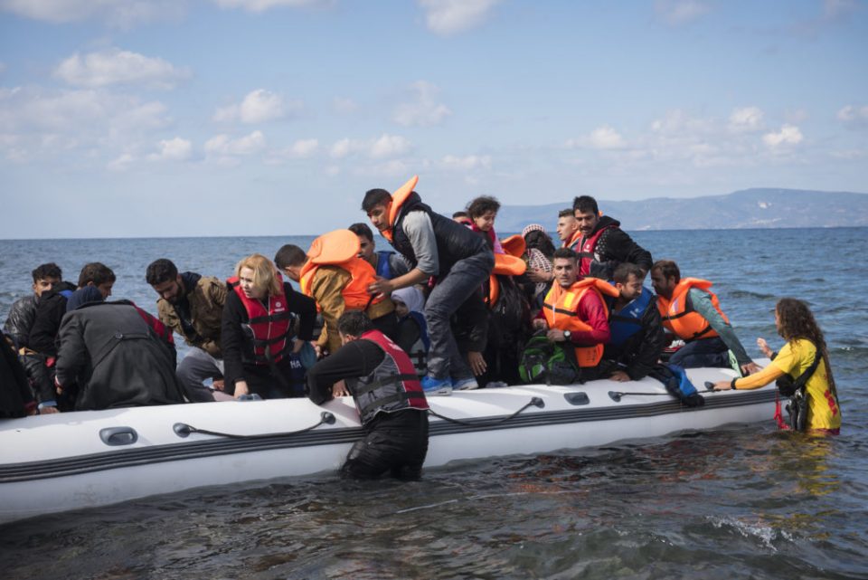 Yunanistan Lesbos Adası, 25 Ekim 2015. Gönüllü bir can kurtaran göçmenlerin bottan inmelerine yardım ediyor. Karşıda Türkiye kıyısı görünür durumda. 